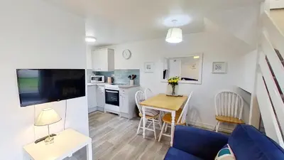 a living room and kitchen with a table and a blue couch at 46 Strawberry Hill, Tolroy Manor in Hayle