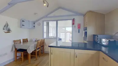 a kitchen with a counter and a table with chairs at G23 Norda, Riviere Towans in Hayle