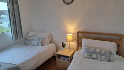 a bedroom with two beds and a lamp on a night stand at G23 Norda, Riviere Towans in Hayle
