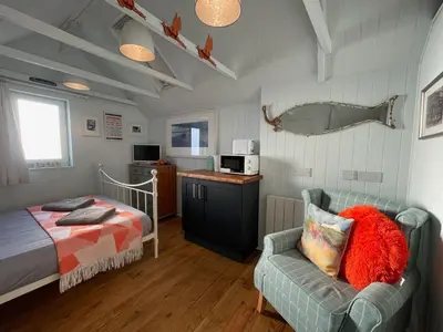 a bedroom with a bed and a couch and a chair at Cilia Marys Annexe St Teath in Saint Teath