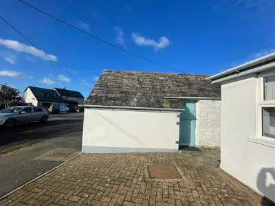 a white building with a blue door on a street at Cilia Marys Annexe St Teath in Saint Teath