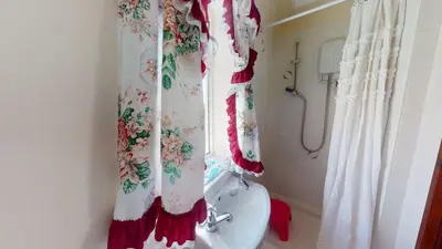 a bathroom with a shower curtain and a toilet and a window at D53 Bide A Wee, Riviere Towans in Hayle