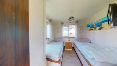 a small room with two beds and a window at D53 Bide A Wee, Riviere Towans in Hayle