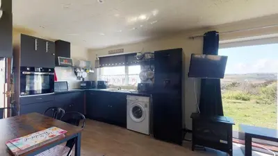 a kitchen with black cabinets and a washer and dryer at D54 Wheal Shoat, Riviere Towans in Hayle