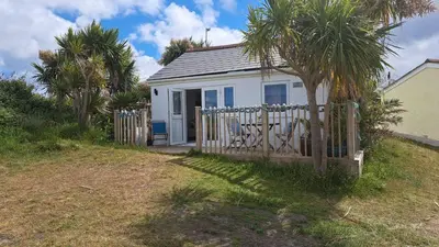 a small white house with a fence and palm trees at A17 Placerville, Riviere Towans in Hayle