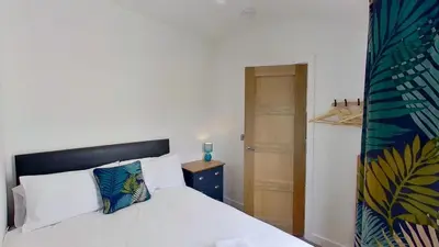 a bedroom with a white bed and a wooden door at A17 Placerville, Riviere Towans in Hayle