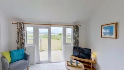 a living room with a chair and a television at A17 Placerville, Riviere Towans in Hayle