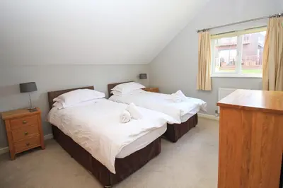 two twin beds in a bedroom with a window at Holiday lodge, on-site watersports, Retallack Resort in Saint Columb Major