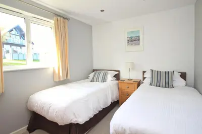 two beds in a room with two windows at Holiday lodge, on-site watersports, Retallack Resort in Saint Columb Major