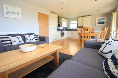 a living room with a couch and a table at Holiday lodge, on-site watersports, Retallack Resort in Saint Columb Major