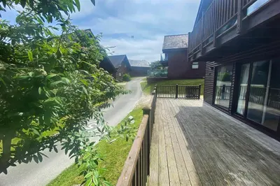 a walkway next to a building next to a building at Holiday lodge, on-site watersports, Retallack Resort in Saint Columb Major