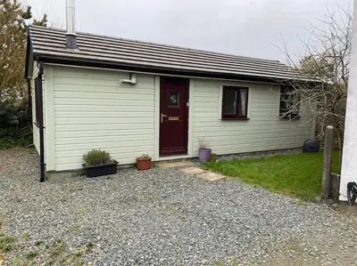 a small white house with a red door at Idyllic Cornish Retreat At Puffin Lodge in Helston