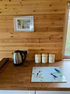 a kitchen with wooden walls and a counter with a tea kettle at Idyllic Cornish Retreat At Puffin Lodge in Helston