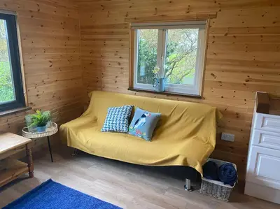 a yellow couch in a room with wooden walls at Idyllic Cornish Retreat At Puffin Lodge in Helston