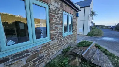 a brick house with two windows on the side of it at Driftwood in Porthtowan