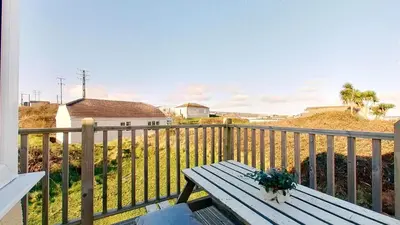 a picnic table on a balcony with a view of the beach at F08 Carne Michael, Riviere Towans in Hayle
