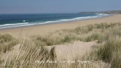 a sandy beach with grass and the ocean at F08 Carne Michael, Riviere Towans in Hayle