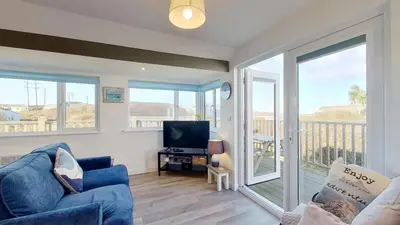 a living room with a blue couch and a television at F08 Carne Michael, Riviere Towans in Hayle