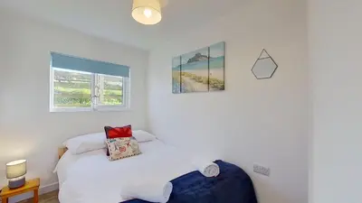 a bedroom with a bed and two pictures on the wall at F08 Carne Michael, Riviere Towans in Hayle