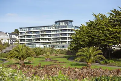 a large building with palm trees in front of it at Oceans Eleven - Sea view - Secure parking - Footsteps from beach in Falmouth