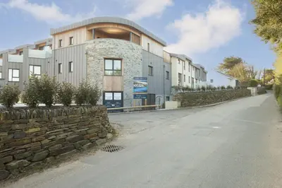 a building with a stone wall next to a street at Harlyn Penthouse, Harlyn Bay - 1 pet accepted - Free Wi-fi - Sea View in St Merryn