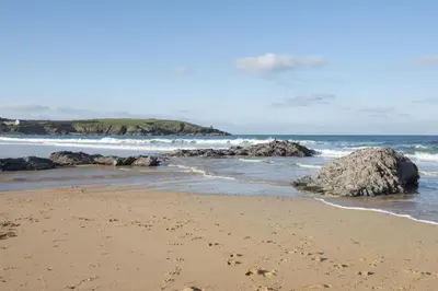 a sandy beach with rocks in the ocean at Harlyn Penthouse, Harlyn Bay - 1 pet accepted - Free Wi-fi - Sea View in St Merryn