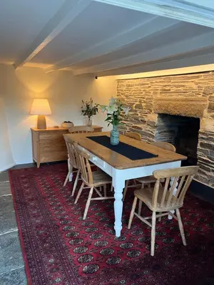 a dining room with a table and chairs and a fireplace at Traditional coastal cottage in Cornwall in Saint Teath