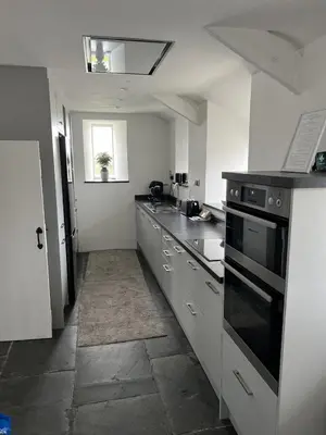 a kitchen with white counters and a stove top oven at Traditional coastal cottage in Cornwall in Saint Teath