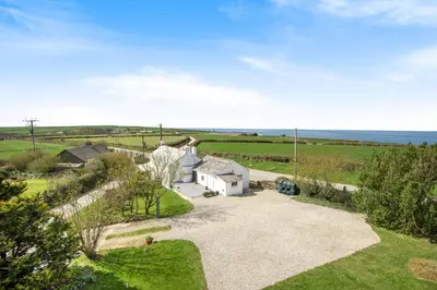 an aerial view of a house with the ocean in the background at Traditional coastal cottage in Cornwall in Saint Teath