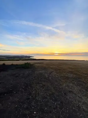 an empty field with the sunset in the background at Traditional coastal cottage in Cornwall in Saint Teath