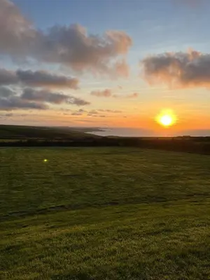 a sunset over a field with the sun in the sky at Traditional coastal cottage in Cornwall in Saint Teath