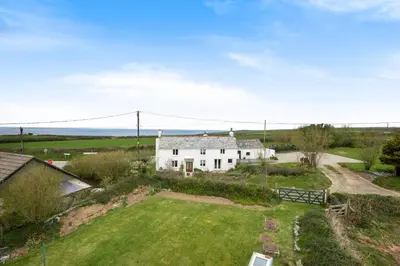 an aerial view of a white house with a yard at Traditional coastal cottage in Cornwall in Saint Teath