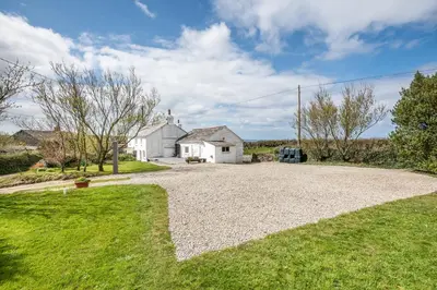 a house with a gravel driveway in front of a house at Traditional coastal cottage in Cornwall in Saint Teath