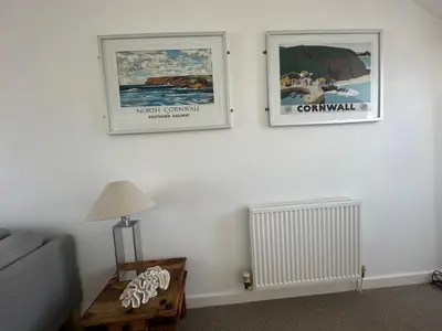 two pictures on a wall with a couch and a table at Beach house with expansive sea views! in Newquay