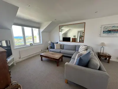 a living room with a couch and a table and a mirror at Beach house with expansive sea views! in Newquay