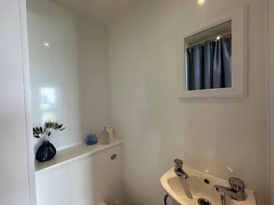 a white bathroom with a sink and a mirror at Beach house with expansive sea views! in Newquay