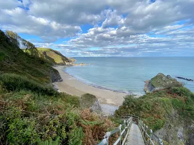 a wooden path leading to a beach with the ocean at About Time Meva - stylish two-bedroom, dog-friendly home-from-home with parking and garden in Mevagissey