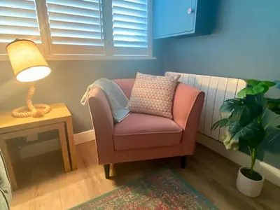 a chair in a room with a lamp and a plant at About Time Meva - stylish two-bedroom, dog-friendly home-from-home with parking and garden in Mevagissey