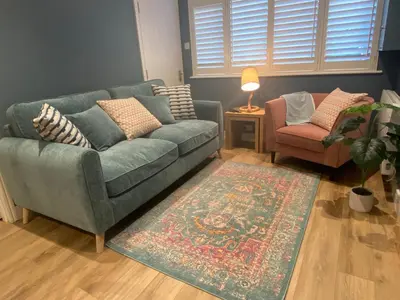 a living room with a green couch and a chair at About Time Meva - stylish two-bedroom, dog-friendly home-from-home with parking and garden in Mevagissey