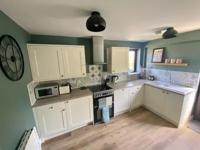 a kitchen with white cabinets and a stove at About Time Meva - stylish two-bedroom, dog-friendly home-from-home with parking and garden in Mevagissey