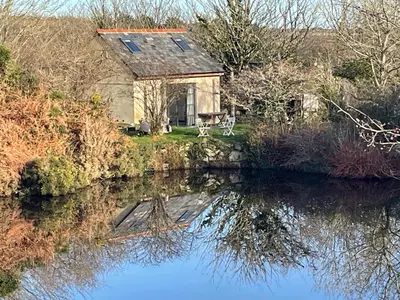a house next to a river with its reflection in the water at Tresahor Studio with sauna in Falmouth