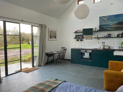 a kitchen with green cabinets and a table at Tresahor Studio with sauna in Falmouth