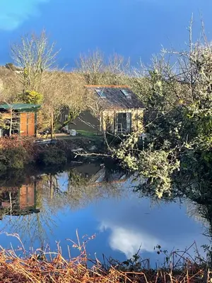 a house reflected in the water of a pond at Tresahor Studio with sauna in Falmouth