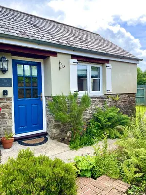a house with a blue door and some plants at The Cowshed - Cottage in Cornwall in Jacobstow