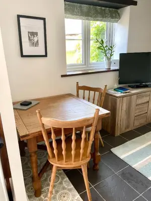a dining room with a wooden table and a television at The Cowshed - Cottage in Cornwall in Jacobstow