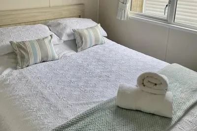 a white bed with a towel on top of it at 2 Bedrooms Sleeps 6 Fast WiFi Pet Friendly in Newquay