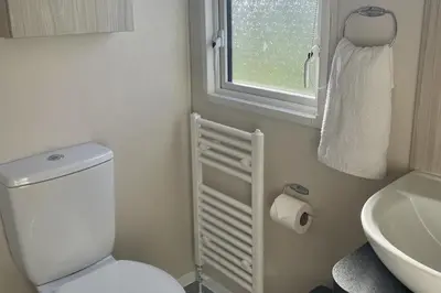 a bathroom with a toilet and a sink and a window at 2 Bedrooms Sleeps 6 Fast WiFi Pet Friendly in Newquay
