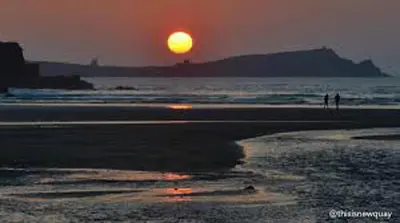 a sunset on a beach with the sun in the distance at 2 Bedrooms Sleeps 6 Fast WiFi Pet Friendly in Newquay