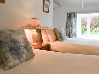 two beds in a bedroom with a lamp and a window at Madderhay - Uk43512 in Lostwithiel