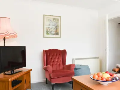 a living room with a red chair and a television at Madderhay - Uk43512 in Lostwithiel
